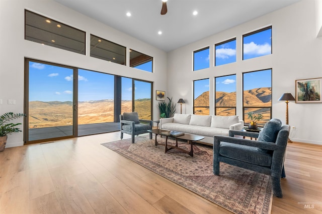 living area featuring recessed lighting, wood finished floors, a towering ceiling, and baseboards