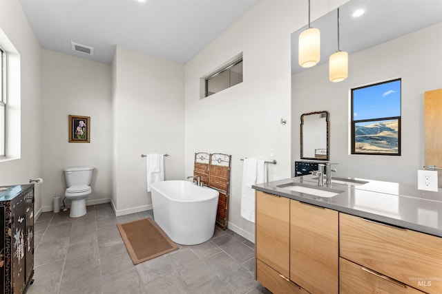 bathroom with visible vents, a freestanding bath, vanity, and toilet