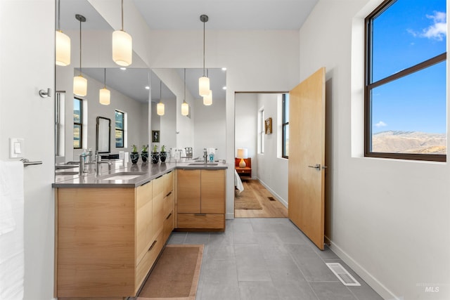 full bathroom with double vanity, a sink, visible vents, and baseboards