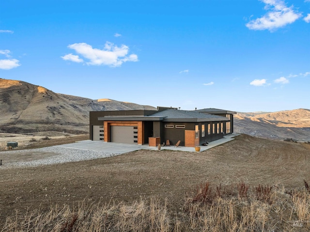 view of front of property with a garage, a mountain view, and driveway