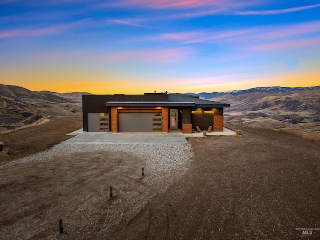 contemporary home featuring concrete driveway, an attached garage, and a mountain view