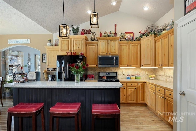 kitchen with electric range, black fridge, stainless steel microwave, light countertops, and vaulted ceiling