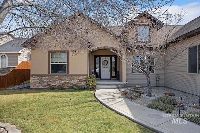 view of front of property with stucco siding, stone siding, a front yard, and fence