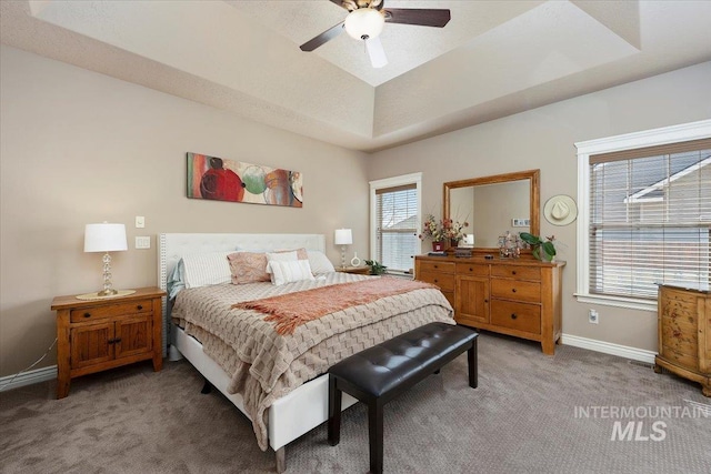 bedroom featuring baseboards, light carpet, a raised ceiling, and a ceiling fan