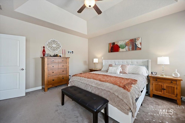 bedroom with light carpet, baseboards, a raised ceiling, and ceiling fan