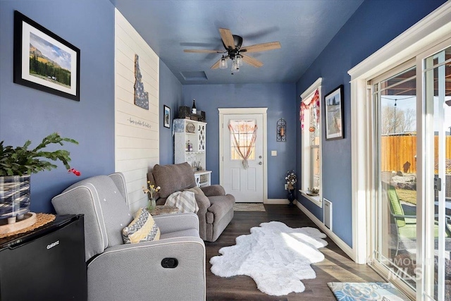 interior space with a ceiling fan, baseboards, and wood finished floors