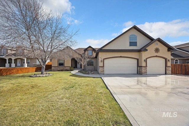 view of front of house featuring a front lawn, concrete driveway, fence, and stone siding