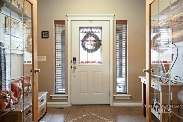 foyer featuring tile patterned floors, visible vents, and baseboards