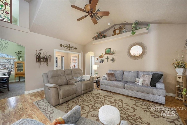 living room with high vaulted ceiling, a ceiling fan, wood finished floors, arched walkways, and baseboards