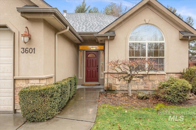 entrance to property featuring stone siding, roof with shingles, and stucco siding