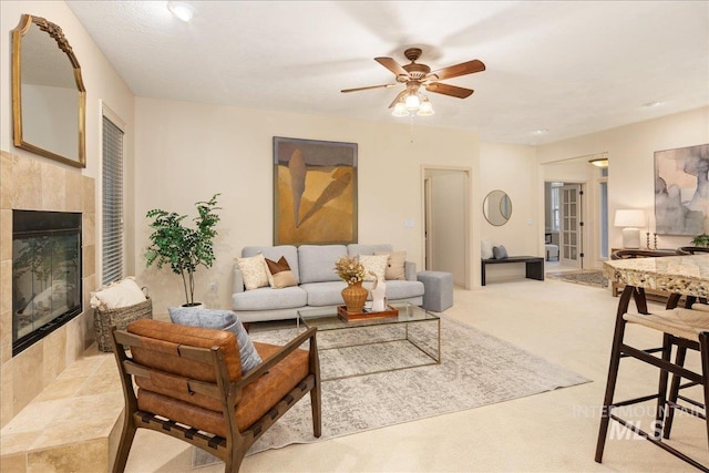 living room featuring light carpet, ceiling fan, and a tiled fireplace