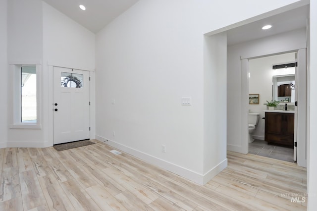 foyer entrance with high vaulted ceiling and light hardwood / wood-style flooring