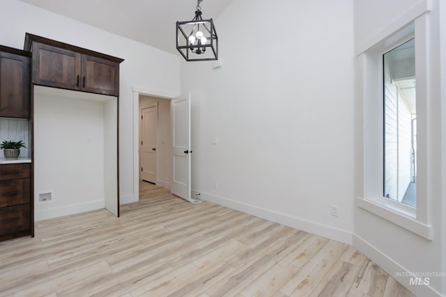 unfurnished dining area featuring a notable chandelier and light hardwood / wood-style flooring