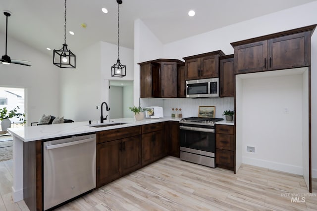 kitchen with sink, hanging light fixtures, appliances with stainless steel finishes, kitchen peninsula, and decorative backsplash