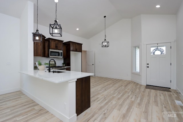 kitchen with sink, pendant lighting, light wood-type flooring, and kitchen peninsula