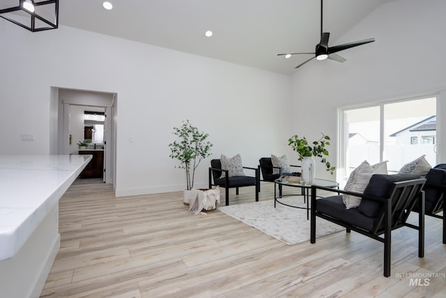 living room featuring light hardwood / wood-style flooring, high vaulted ceiling, and ceiling fan