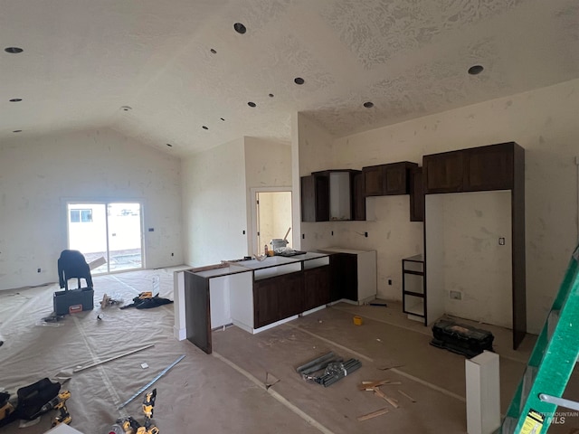 kitchen featuring dark brown cabinets and high vaulted ceiling