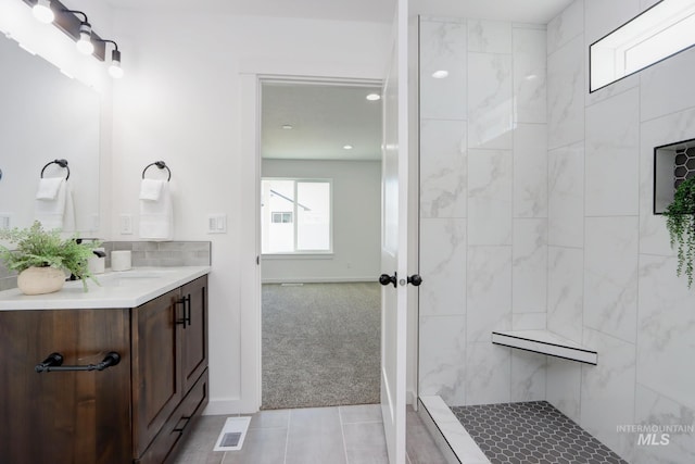 bathroom with a tile shower and vanity