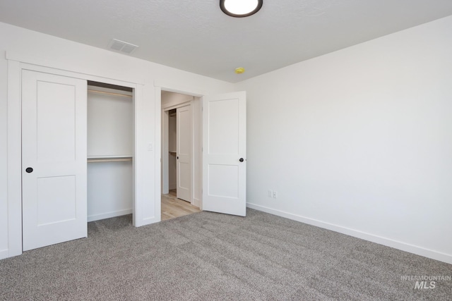 unfurnished bedroom with light colored carpet and a closet