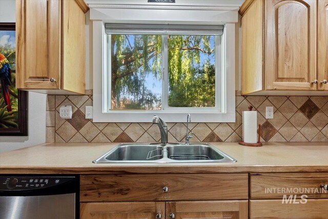 kitchen featuring stainless steel dishwasher, light brown cabinets, a sink, and light countertops