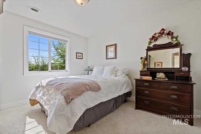 bedroom featuring visible vents, baseboards, and light carpet