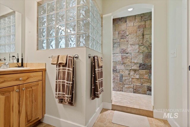 bathroom featuring vanity, baseboards, and walk in shower