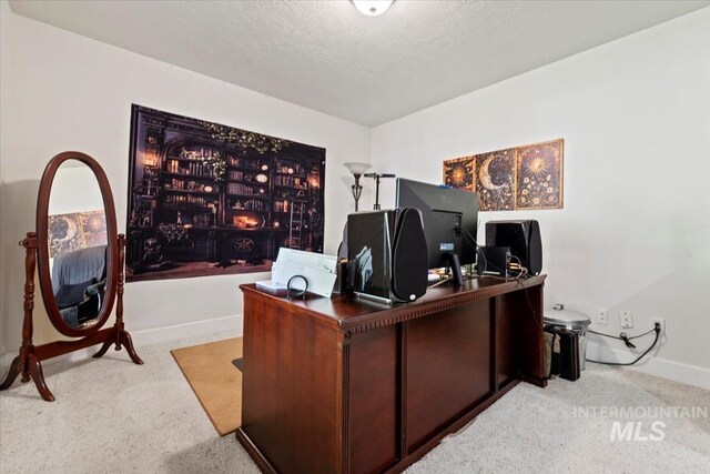 carpeted office space featuring baseboards and a textured ceiling
