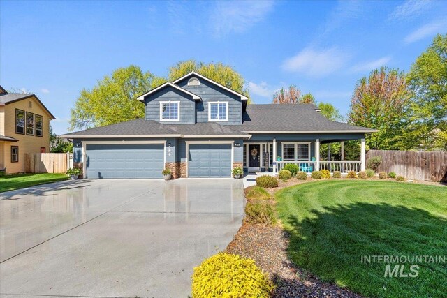 traditional-style house featuring fence, covered porch, driveway, and a front yard
