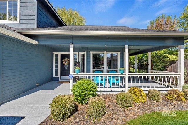 entrance to property with a porch and a shingled roof