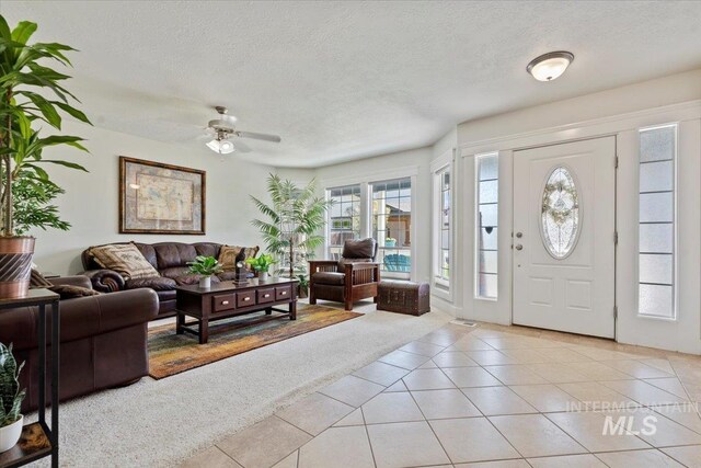 foyer entrance with a ceiling fan, a textured ceiling, light carpet, and light tile patterned floors