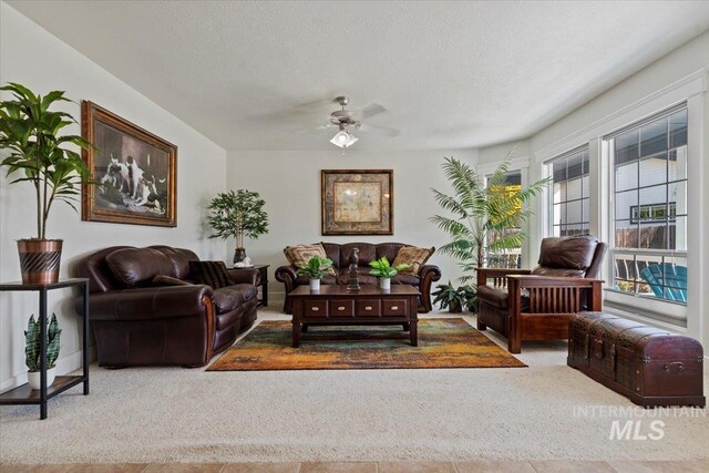 carpeted living area featuring a textured ceiling and ceiling fan