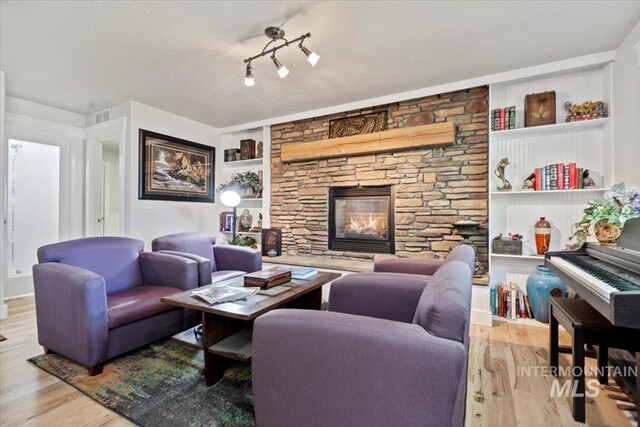 living room with built in features, wood finished floors, and a fireplace