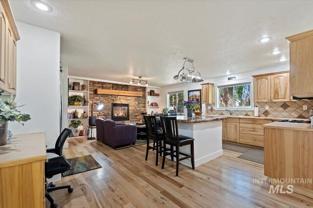 kitchen featuring light brown cabinetry, a center island, light wood-style flooring, and open floor plan