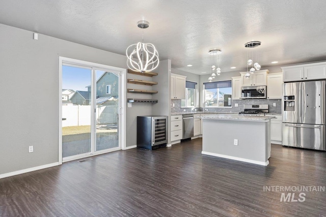 kitchen with decorative light fixtures, a center island, stainless steel appliances, and white cabinetry