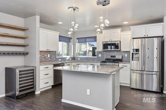 kitchen with white cabinets, beverage cooler, a kitchen island, and appliances with stainless steel finishes