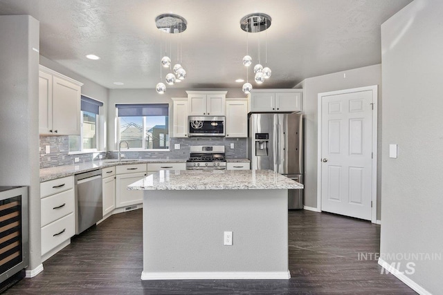 kitchen with pendant lighting, a center island, sink, appliances with stainless steel finishes, and beverage cooler