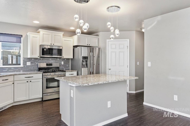 kitchen featuring decorative backsplash, stainless steel appliances, pendant lighting, white cabinets, and a kitchen island