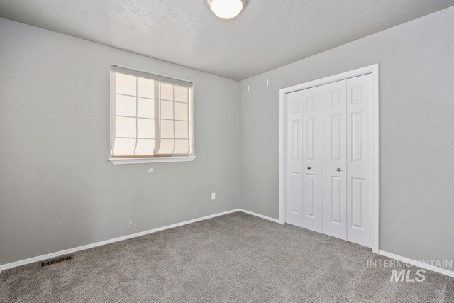 unfurnished bedroom featuring a closet, carpet floors, and a textured ceiling