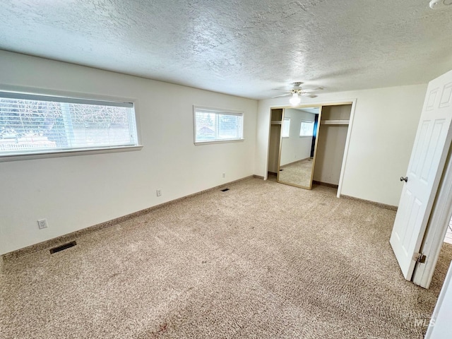 unfurnished bedroom featuring a ceiling fan, baseboards, visible vents, a textured ceiling, and light carpet