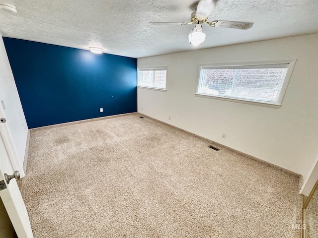 spare room with visible vents, baseboards, carpet floors, a textured ceiling, and a ceiling fan