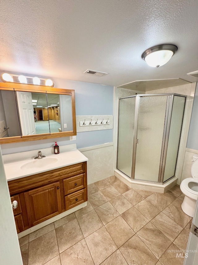 full bath featuring visible vents, vanity, a shower stall, and a textured ceiling