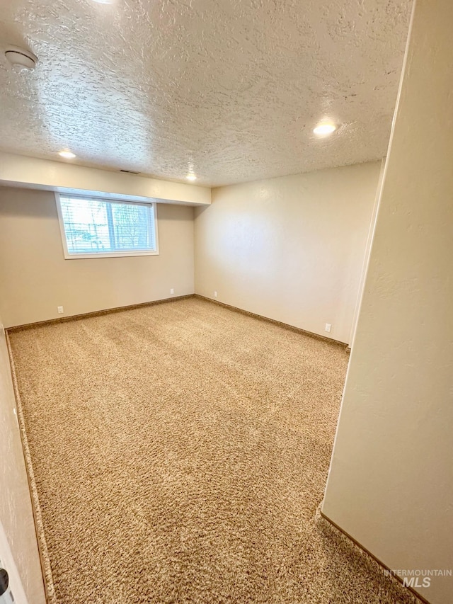 basement with baseboards, carpet floors, and a textured ceiling