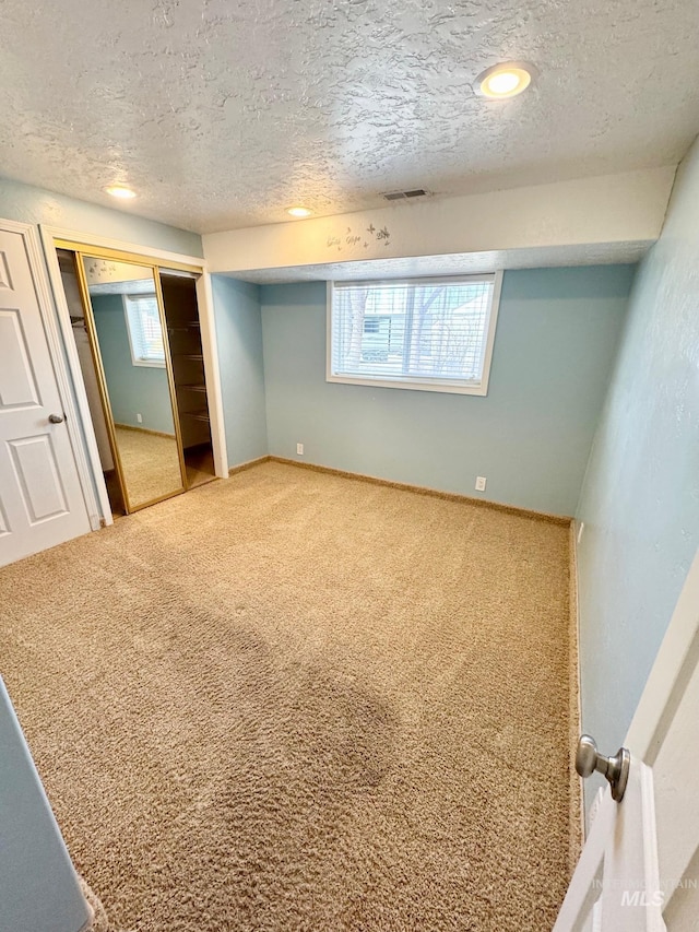 unfurnished bedroom featuring multiple windows, carpet floors, and a textured ceiling