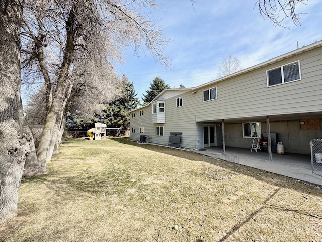 rear view of property with a playground, a patio area, and a lawn