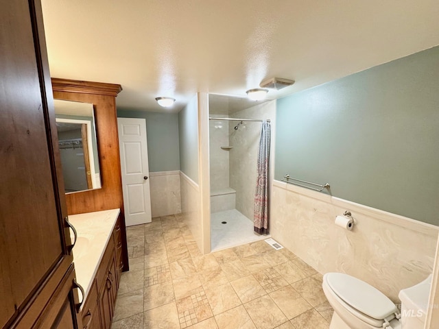 bathroom with a wainscoted wall, a shower with curtain, vanity, and toilet