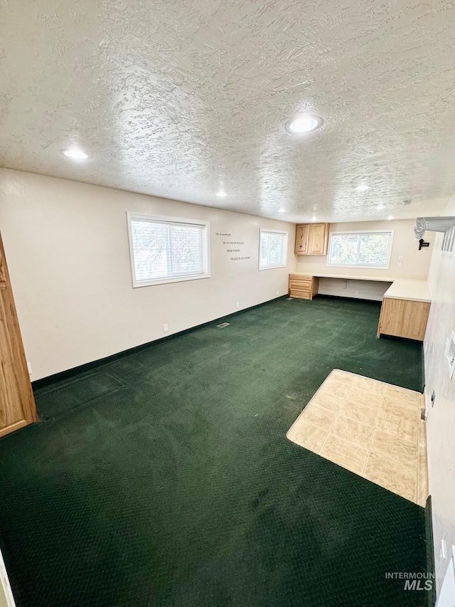 additional living space with recessed lighting, baseboards, a textured ceiling, and dark carpet