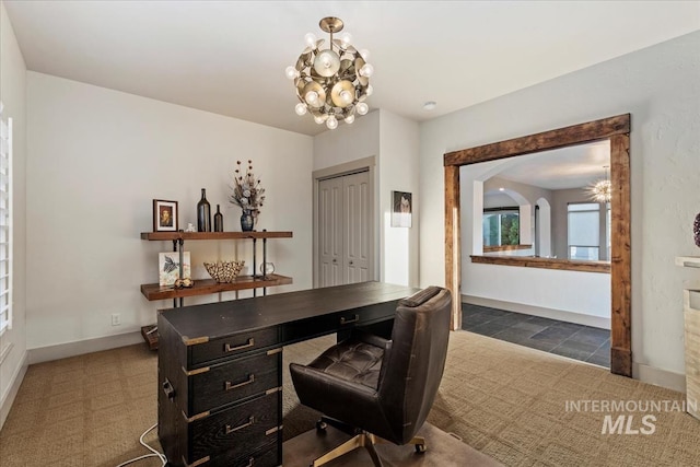 home office featuring baseboards, arched walkways, a notable chandelier, and carpet