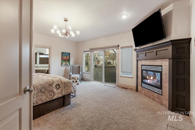 bedroom with carpet, a fireplace, ensuite bathroom, a notable chandelier, and access to outside