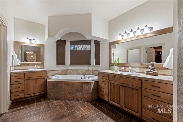 bathroom with a bath, two vanities, and a sink