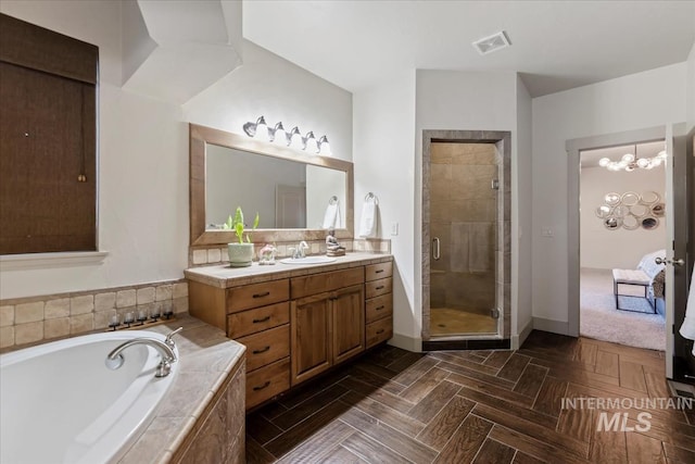 bathroom featuring vanity, baseboards, visible vents, a shower stall, and a garden tub